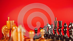 Close up of black chess pieces on board. Two rows of wooden figures on chessboard on red background. Concept of