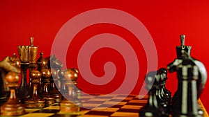 Close up of black chess pieces on board. Two rows of wooden figures on chessboard on red background. Concept of