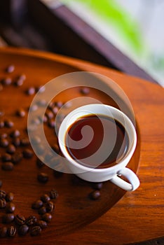 Close-up of a black coffee cup and coffee beans  on wood background