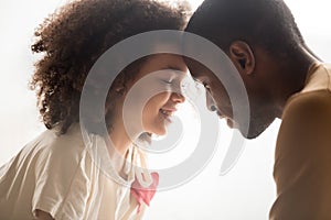 Close up of black dad and daughter touch foreheads