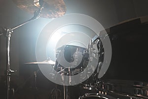 Close-up black drums A modern drum set prepared for playing in a dark rehearsal room on stage with a bright spotlight