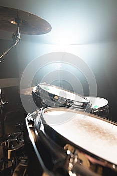 Close-up black drums A modern drum set prepared for playing in a dark rehearsal room on stage with a bright spotlight