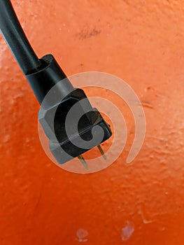 Close up black electric cable isolated on orange wall background.