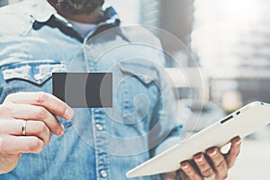 Close-up of black empty credit, business, calling, visiting card and digital tablet in hand of young businessman.