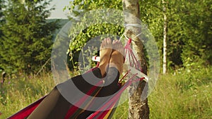 Close-up of black female barefoot legs lying in hammock over scenic nature