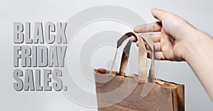 Close-up of black friday sales text, on the grey background near eco paper in male hand.