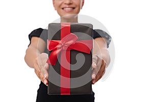 Close-up of a black gift box with red ribbon in the hands of smiling woman isolated on white background with copy space.