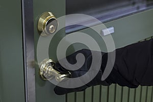 Close up of black gloves on safety door handle. Break-in - burglar - concept image.