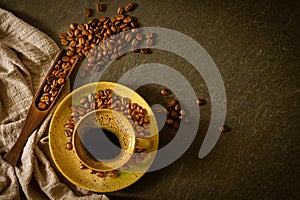 Close-up of Black hot coffee for morning with milk foam in brown ceramic cup and napkin with coffee beans roasted in sack on dark