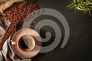 Close-up of Black hot coffee for morning with milk foam in old pink ceramic cup and napkin with coffee beans roasted in sack on da