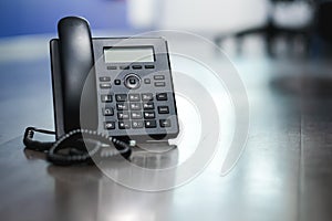 Close Up Black ip phone is placed on a wooden floor in the office