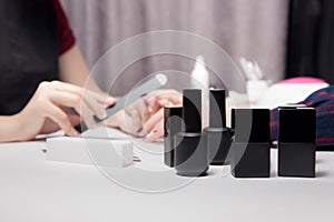 Close-up black jars, bottles, containers of nail polish. Process creating manicure beautiful female hands