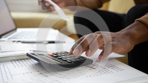 Close up black man hand using calculator and laptop.