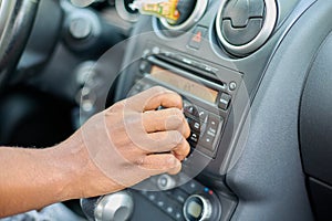 Close-up of a black man& x27;s hand adjusts the volume of the car stereo system.