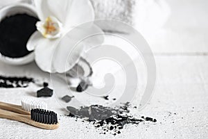 Close up of black natural teeth whitening powder and toothbrushes copy space