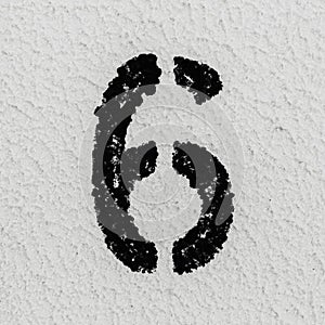 Close-up of black painted number of 6 on background of grey textured wall.