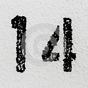 Close-up of black painted number of 14 on background of grey textured wall. photo