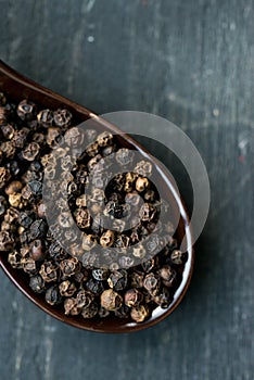Close up black peppercorn in spoon dark background