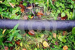 Close-up of black plastic pipes with geotextile lying on the grass