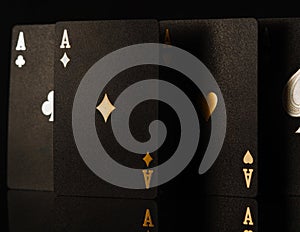Close-up. Black poker cards with gold embossing on a black background, three aces. Gambling, poker, casino, gambling house, online
