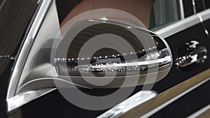 The close up of black rear view mirror of luxurious car.