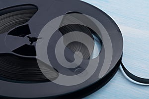 Close-up of a black reel with magnetic tape for recording music, retro version, on a blue background