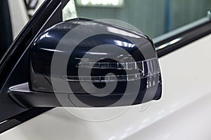 Close-up of the black side mirror of the car body in the design of a white suv