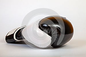 Close-up on a black side turned boxing glove for a blow on a white background.