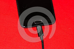 Close-up of black smartphone charging battery with an USB cable on wooden table with copy space