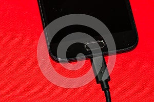 Close-up of black smartphone charging battery with an USB cable on wooden table with copy space