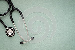 Close-up of Black stethoscope of doctor for checkup on light green background.