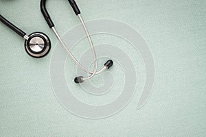 Close-up of Black stethoscope of doctor for checkup on light green background.