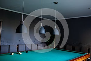 Close up of black stylish lamps hang over billiard table. Leisure activity interior design elements.