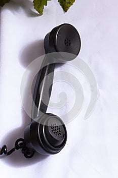 Close-up of black telephone horn on white cloth. Seniority seen from above to make calls