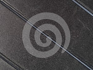 Close-up of black textured fabric with diagonal stitched lines, showcasing fine weave detail and durable material design. photo