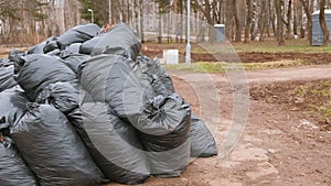Close-up of black trash bags piled up In the city park.