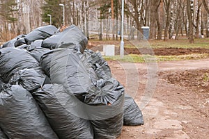 Close-up of black trash bags piled up In the city park.