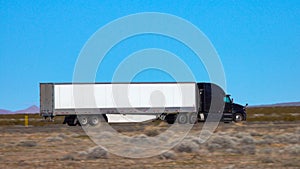 CLOSE UP: Black truck speeds along the interstate highway crossing a desert