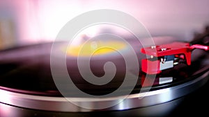 Close-up of black vinyl record, disk is spinning, colored lights, analogue retro music concept, audio experience, relaxation,