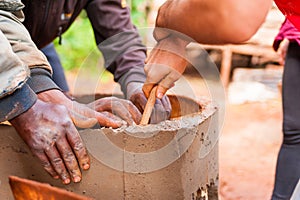 Close up of black and white hands cooperating to build cement water well in africa village