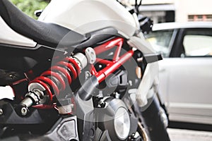 close up black and white motorcycle at city space with red colored shock absorber. selective focus. city bike