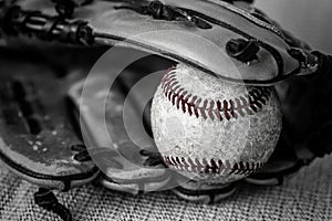 Close up black and white shot of a vintage baseball and glove.