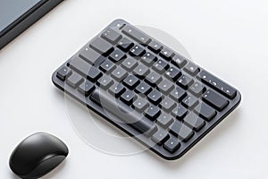 Close-up of a black wireless mouse on a white desk, with a blurred keyboard in the background, perfect for technology or