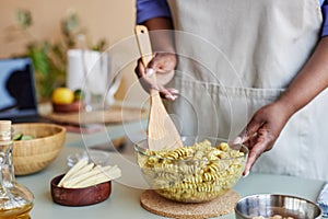 Close up of black woman mixing pasta in bowl cooking in kitchen