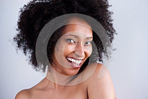 Close up black woman with naked shoulders smiling on gray background