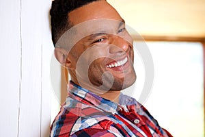 Close up black young man leaning against wall and laughing