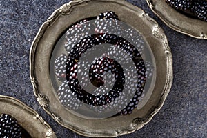 Close up blackberries in plate on dark table background