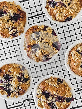 Close up blackcurrant muffins with oatmeal crumble on a baking rack on a light background, top view