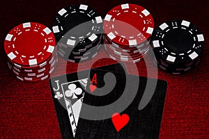 A close up of Blackjack hand with unique black, white and red cards with Black and Red Clay poker chips on a Dark Red Felt table