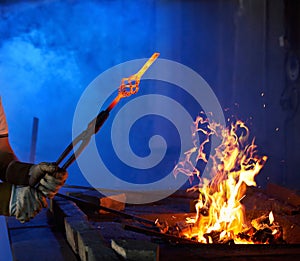 Close up of blacksmith holding forceps with metal over fire